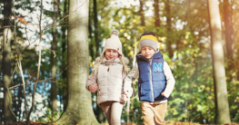 Zwei kleine Kinder wandern Hand in Hand zusammen durch den Wald und entdecken die Natur